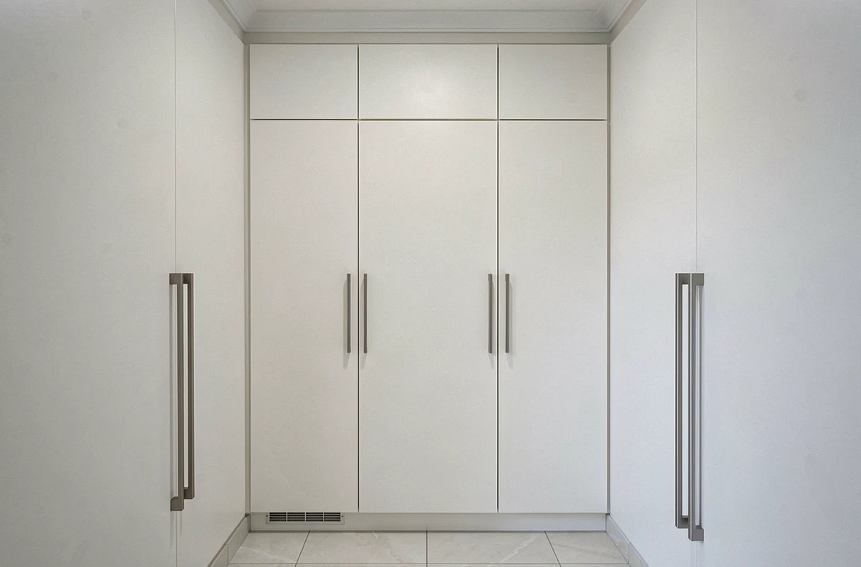 Cuisine équipée de meubles hauts jusqu'au plafond en laque blanche mate, supprimant le vide inutile au-dessus des placards et maximisant le rangement vertical